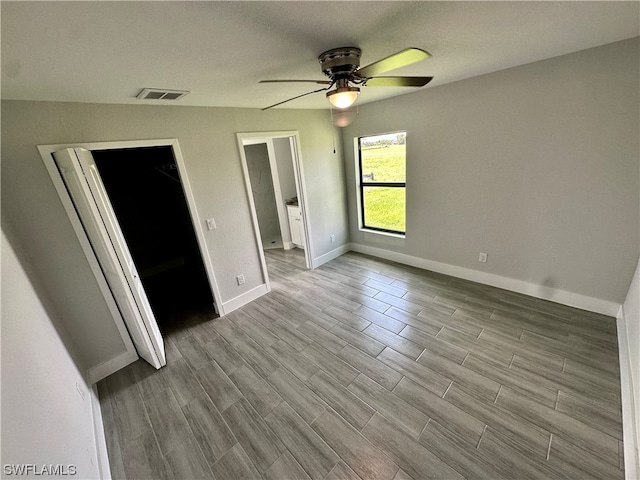 unfurnished bedroom with a closet, a spacious closet, ceiling fan, and light wood-type flooring