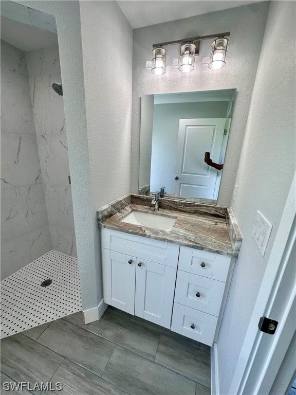 bathroom featuring tile floors, a tile shower, and vanity