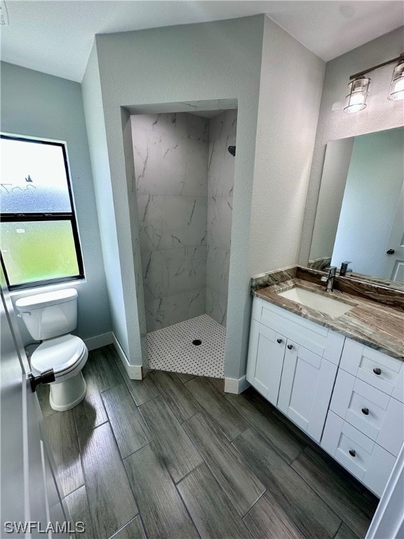 bathroom featuring a tile shower, oversized vanity, and toilet