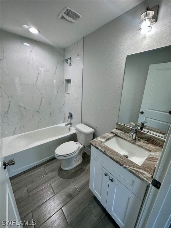 full bathroom with vanity, tiled shower / bath combo, tile flooring, and toilet