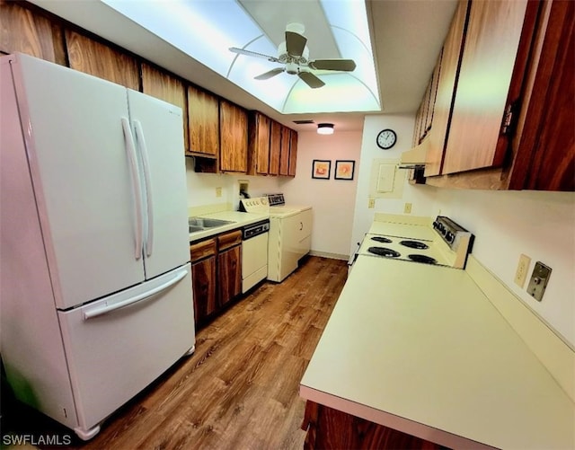 kitchen featuring white appliances, a ceiling fan, washer and dryer, light countertops, and light wood-type flooring