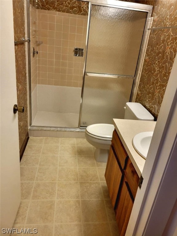 bathroom with toilet, vanity, tile patterned floors, a stall shower, and wallpapered walls