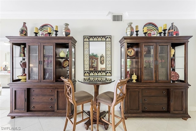 dining space featuring crown molding and light tile flooring