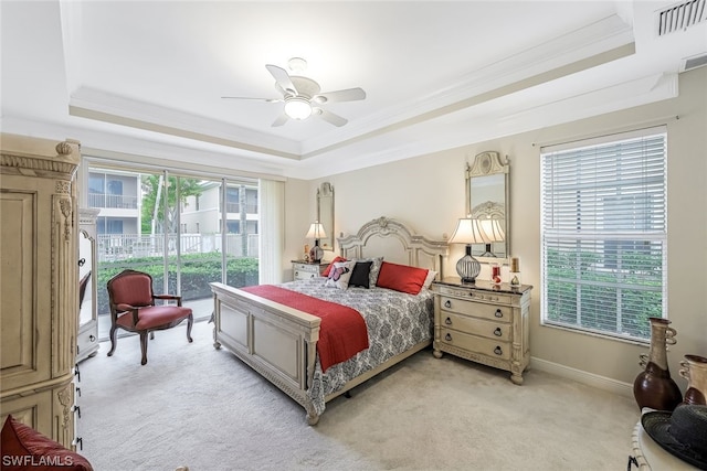 bedroom with light carpet, a tray ceiling, and ceiling fan