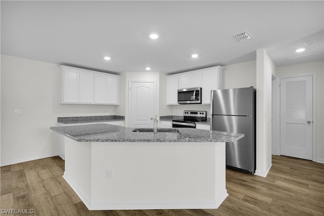 kitchen featuring white cabinets, appliances with stainless steel finishes, a kitchen island with sink, and light wood-type flooring