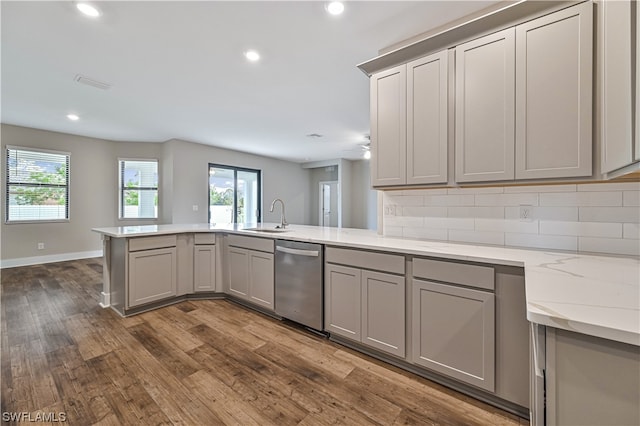 kitchen featuring gray cabinetry, light stone counters, dark hardwood / wood-style floors, and stainless steel dishwasher