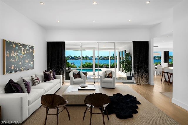 living room with light wood-type flooring and a water view