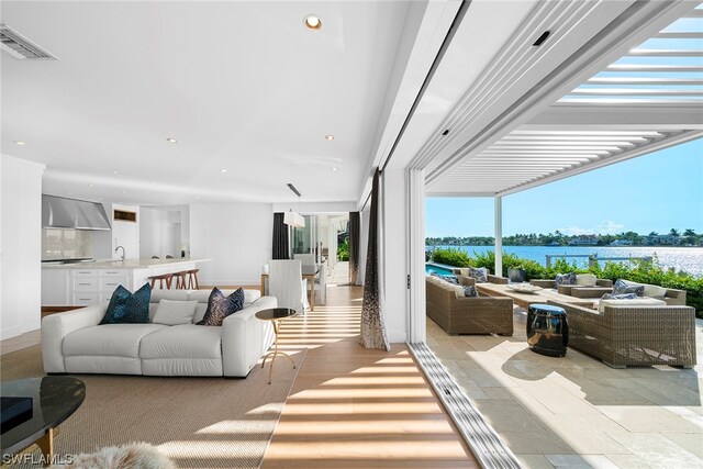 living room featuring light hardwood / wood-style floors, sink, and a water view