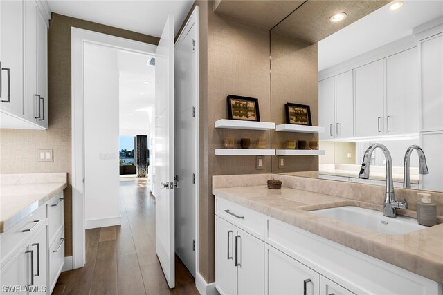 kitchen with white cabinets, hardwood / wood-style flooring, sink, and light stone counters