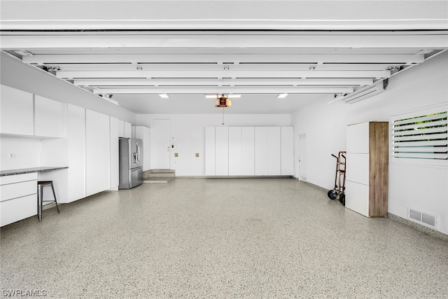 garage featuring a garage door opener and stainless steel fridge