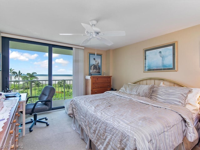 carpeted bedroom featuring expansive windows, a water view, ceiling fan, and access to outside