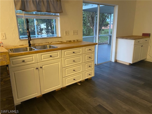 kitchen with plenty of natural light, white cabinets, dark wood-type flooring, and sink