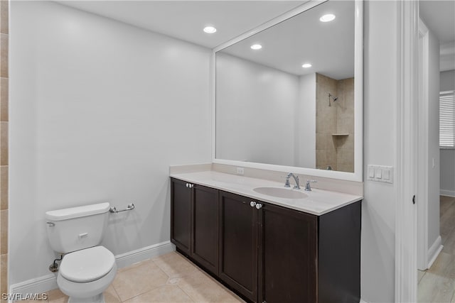 bathroom with vanity, toilet, a tile shower, and tile patterned floors