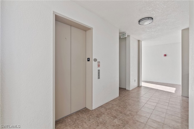 hall with a textured ceiling and elevator