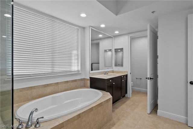 bathroom with vanity, toilet, tile patterned floors, and a relaxing tiled tub