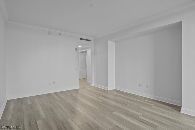 spare room featuring crown molding and light hardwood / wood-style flooring