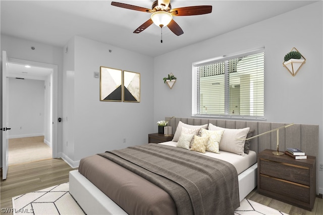 bedroom with multiple windows, ceiling fan, and light hardwood / wood-style floors