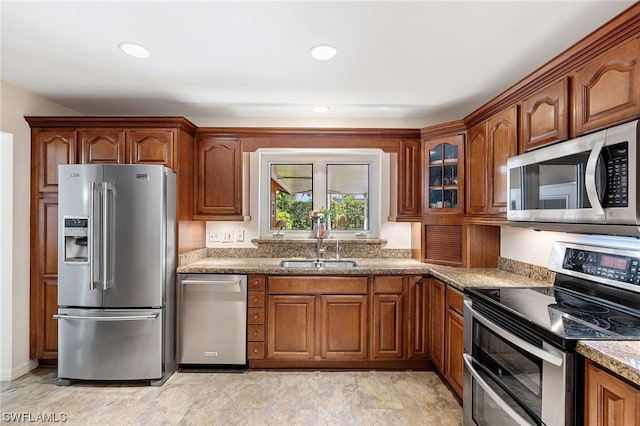 kitchen with light stone countertops, stainless steel appliances, and sink