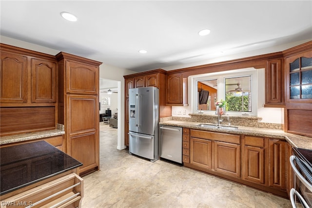 kitchen featuring ceiling fan, sink, stainless steel appliances, and light stone counters