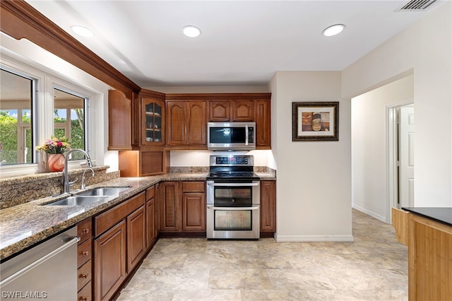 kitchen featuring sink, stainless steel appliances, and dark stone counters