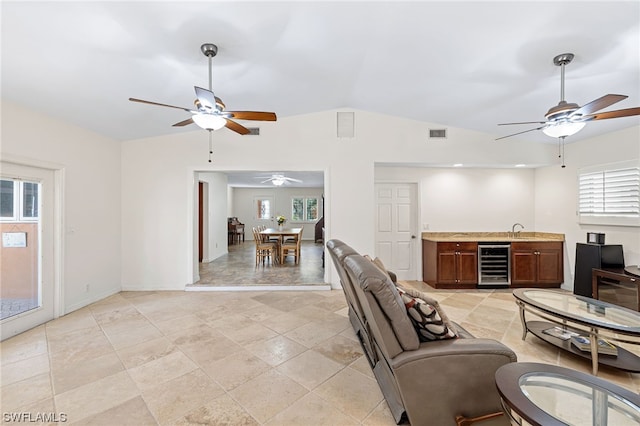 living room featuring ceiling fan, sink, beverage cooler, and vaulted ceiling