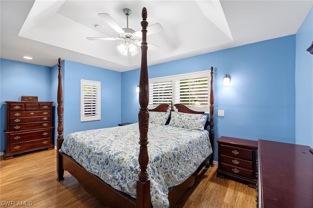 bedroom featuring a tray ceiling, light hardwood / wood-style flooring, and ceiling fan