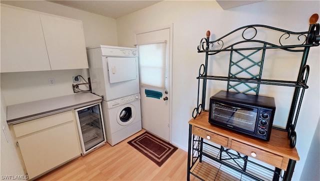 kitchen featuring light wood-type flooring, beverage cooler, white cabinetry, and stacked washer and dryer