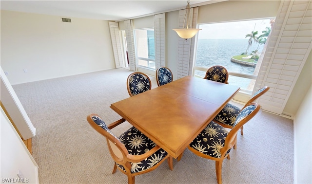 dining area featuring a water view, light colored carpet, and a wealth of natural light