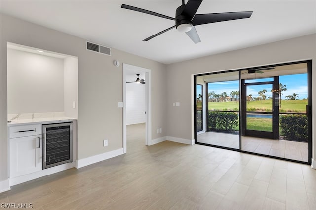 unfurnished living room featuring light wood-type flooring, ceiling fan, and wine cooler