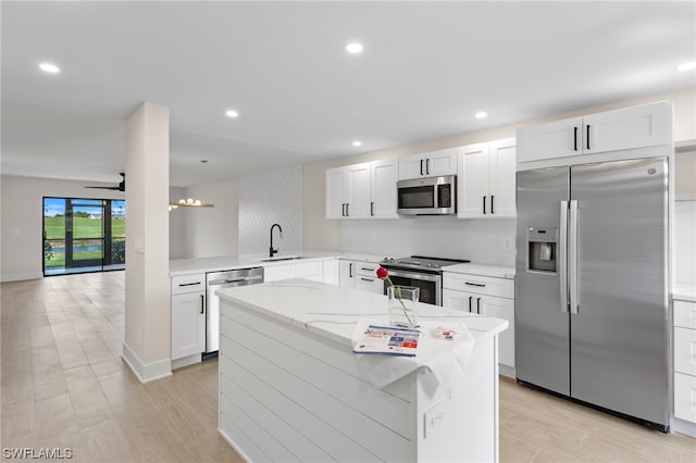 kitchen featuring ceiling fan, sink, appliances with stainless steel finishes, white cabinetry, and light stone counters