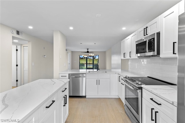 kitchen featuring ceiling fan, appliances with stainless steel finishes, tasteful backsplash, white cabinetry, and light wood-type flooring