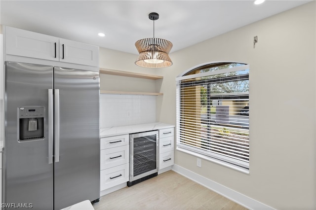 kitchen featuring stainless steel fridge with ice dispenser, light hardwood / wood-style flooring, light stone countertops, beverage cooler, and white cabinetry