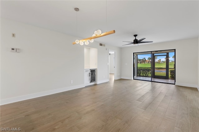 unfurnished living room featuring wine cooler, ceiling fan, and hardwood / wood-style flooring