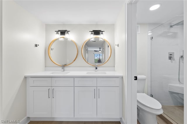 bathroom with hardwood / wood-style flooring, a tile shower, double vanity, and toilet