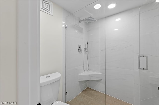 bathroom featuring hardwood / wood-style flooring, walk in shower, and toilet