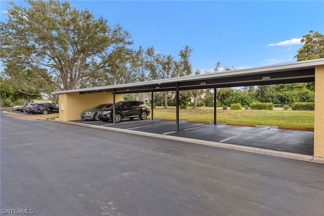 view of car parking featuring a lawn and a carport