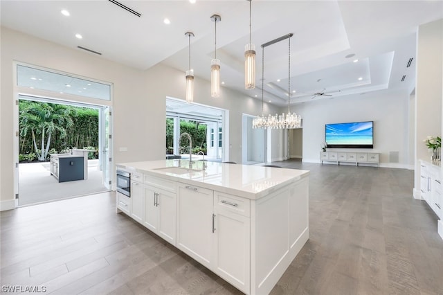 kitchen featuring white cabinets, a tray ceiling, built in microwave, and ceiling fan