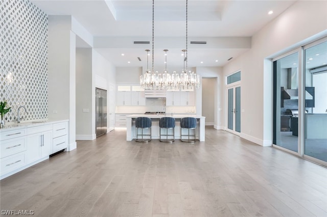 unfurnished living room with a notable chandelier, light hardwood / wood-style floors, and sink