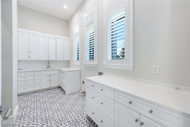 interior space with light tile flooring, hookup for a washing machine, cabinets, and sink