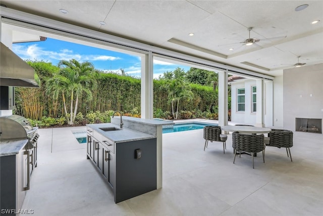 view of patio featuring area for grilling, an outdoor kitchen, ceiling fan, a fenced in pool, and sink