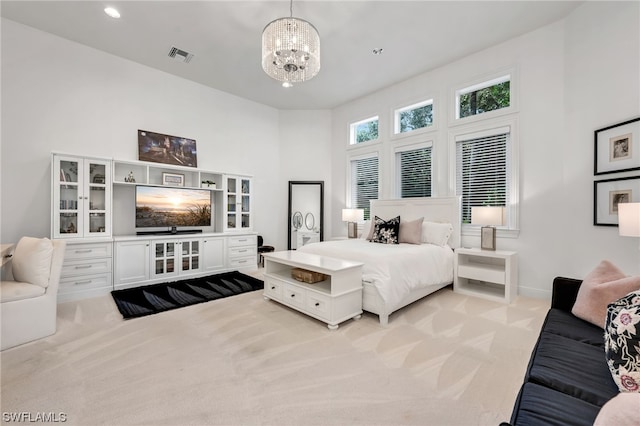 bedroom featuring a chandelier, light colored carpet, and a towering ceiling