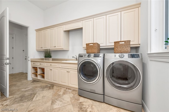 clothes washing area with light tile floors, cabinets, washer and dryer, and sink
