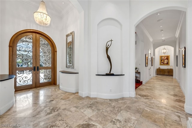 tiled entryway with a notable chandelier, crown molding, french doors, and a towering ceiling
