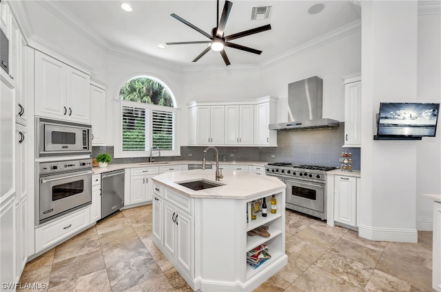 kitchen with ceiling fan, a center island with sink, appliances with stainless steel finishes, wall chimney exhaust hood, and white cabinets