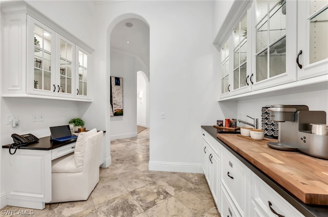 bar with white cabinets, ornamental molding, and light tile floors