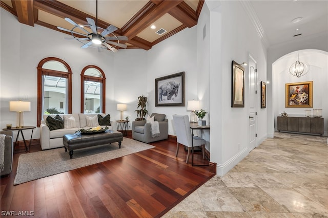living room with light tile floors, crown molding, beamed ceiling, coffered ceiling, and ceiling fan with notable chandelier