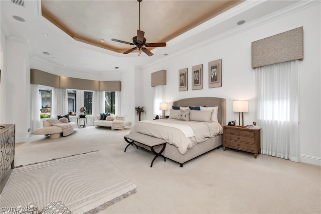 bedroom featuring a raised ceiling, ornamental molding, light colored carpet, and ceiling fan