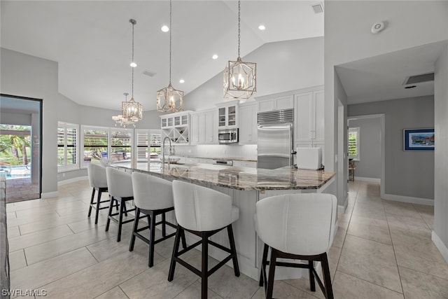 kitchen with white cabinets, hanging light fixtures, appliances with stainless steel finishes, and a breakfast bar area