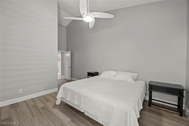 bedroom featuring ceiling fan, baseboards, high vaulted ceiling, and wood finished floors