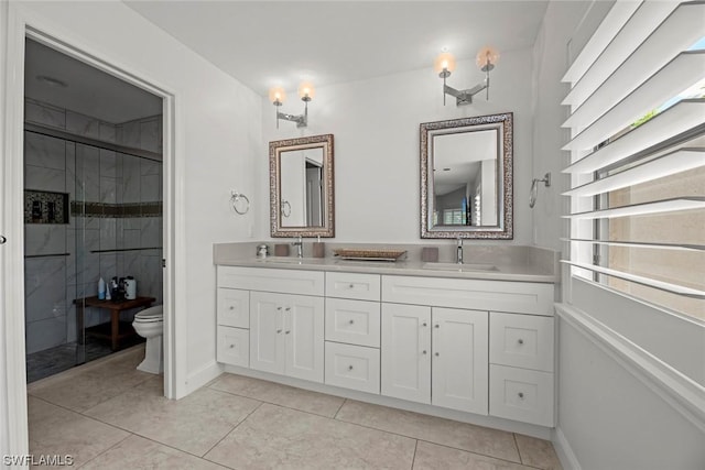 bathroom with baseboards, double vanity, a sink, a shower stall, and toilet